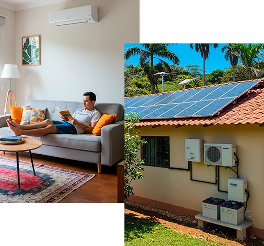 Hombre joven leyendo en un sofá dentro de una sala moderna con aire acondicionado split de 12,000 BTU encendido, ventilador de techo y decoración tropical, mientras la vivienda cuenta con un sistema de paneles solares instalados en el techo, con baterías e inversor solar conectados. Ejemplo de consumo energético doméstico en una casa ubicada en zona rural tropical, con solución fotovoltaica autónoma para climas cálidos como en Colombia.
